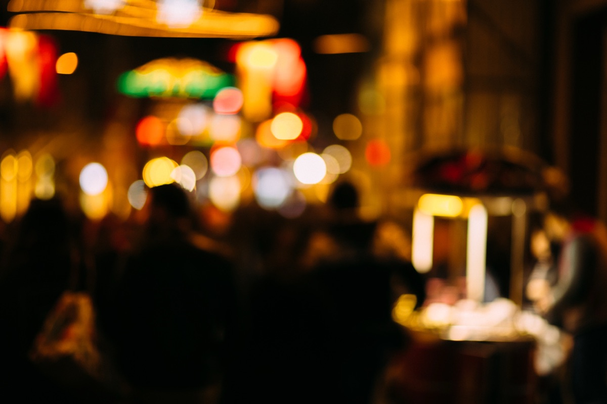 Warm out-of-focus lights of a street food stand and a crowd at night